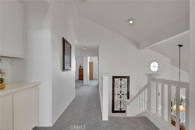 corridor featuring vaulted ceiling with beams, baseboards, light colored carpet, and an upstairs landing