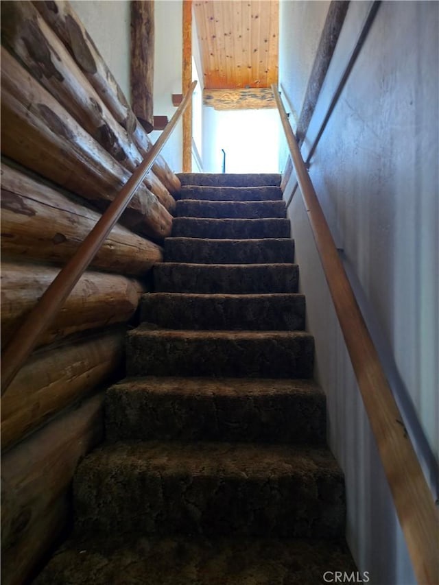 stairs featuring wooden ceiling and log walls