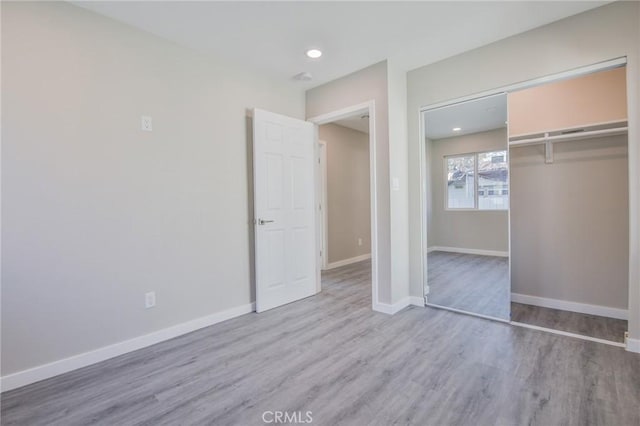 unfurnished bedroom with light wood finished floors, baseboards, a closet, and recessed lighting