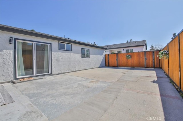 back of house featuring a patio, a fenced backyard, and stucco siding