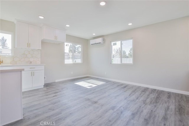 kitchen featuring open floor plan, light countertops, a wall unit AC, and white cabinets