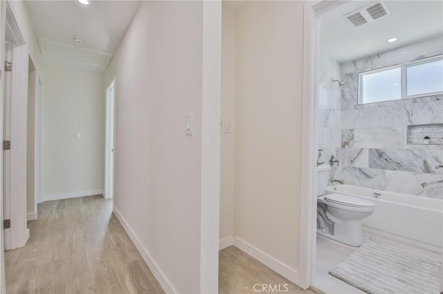 bathroom with toilet, wood finished floors, visible vents, bathing tub / shower combination, and baseboards