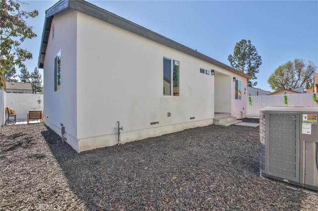 back of house with crawl space, stucco siding, cooling unit, and fence