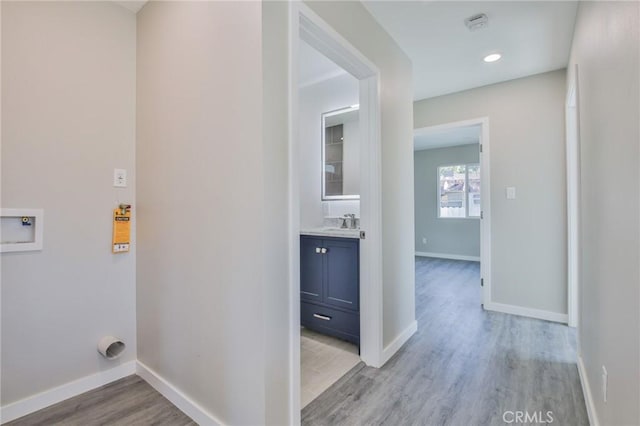 laundry room with hookup for a washing machine, a sink, light wood-style flooring, and baseboards