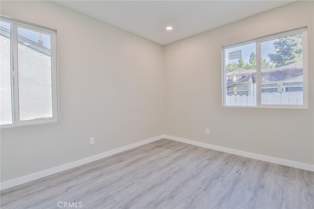 empty room featuring light wood-type flooring, baseboards, and recessed lighting