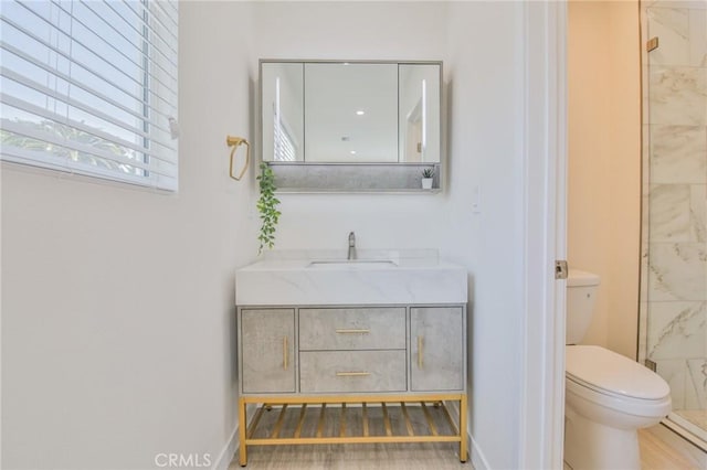 full bathroom featuring a tile shower, vanity, and toilet