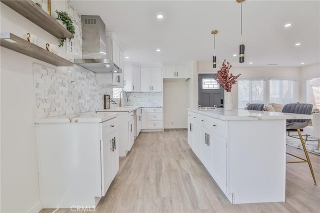 kitchen featuring white cabinets, decorative backsplash, wall chimney exhaust hood, decorative light fixtures, and open shelves