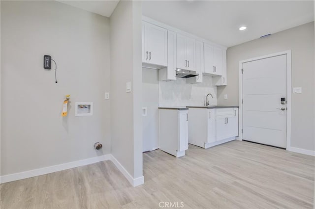 clothes washing area featuring baseboards, light wood-type flooring, washer hookup, a sink, and recessed lighting