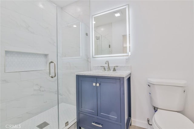 bathroom featuring toilet, a marble finish shower, baseboards, and vanity