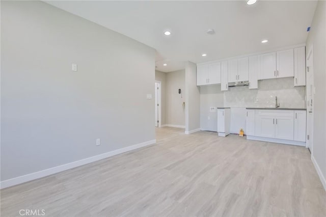 kitchen with under cabinet range hood, baseboards, and white cabinets