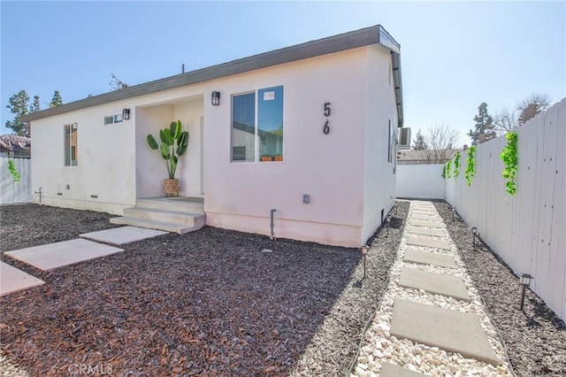 rear view of property featuring crawl space, a fenced backyard, and stucco siding