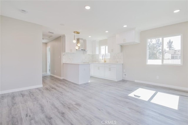 kitchen featuring open floor plan, light countertops, backsplash, and white cabinetry