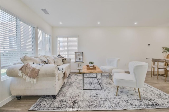 living area with recessed lighting, visible vents, light wood-style flooring, and baseboards