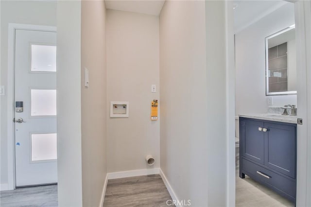 washroom with laundry area, baseboards, light wood finished floors, and a sink