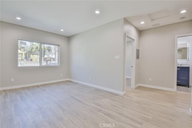 unfurnished room featuring light wood-type flooring, attic access, baseboards, and recessed lighting