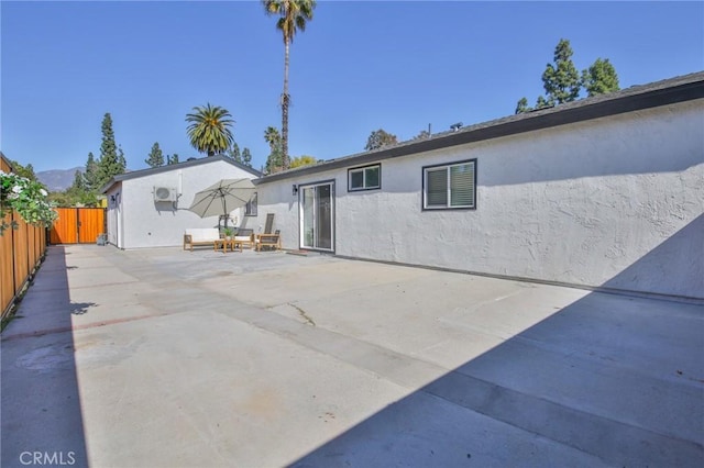 rear view of house featuring a patio, fence, and stucco siding