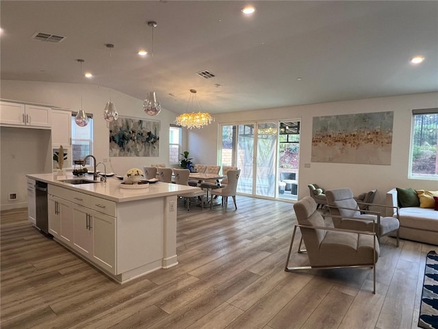 kitchen featuring light countertops, open floor plan, white cabinetry, and a center island with sink