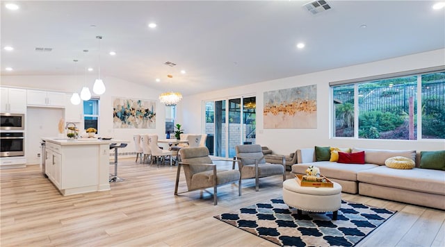 living area featuring light wood finished floors, visible vents, and vaulted ceiling