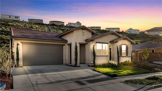 mediterranean / spanish-style home featuring stucco siding, concrete driveway, an attached garage, and a tile roof