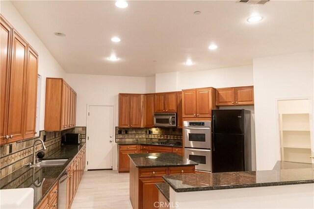 1594 Margit St, Redlands, CA 92374 - kitchen featuring dark stone counters, a sink, stainless steel appliances, tasteful backsplash, and a center island