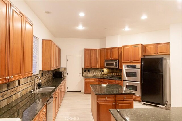 1594 Margit St, Redlands, CA 92374 - kitchen with dark stone counters, decorative backsplash, appliances with stainless steel finishes, a kitchen island, and a sink