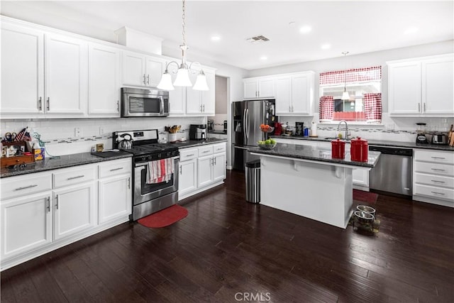 kitchen with stainless steel appliances, pendant lighting, white cabinetry, and a kitchen island