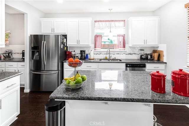 kitchen with stainless steel appliances, dark stone countertops, a sink, and white cabinets