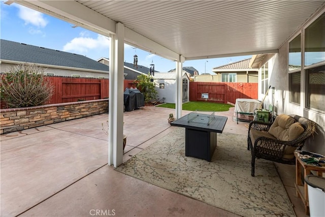 view of patio featuring an outbuilding, a fenced backyard, a storage shed, a grill, and an outdoor living space with a fire pit