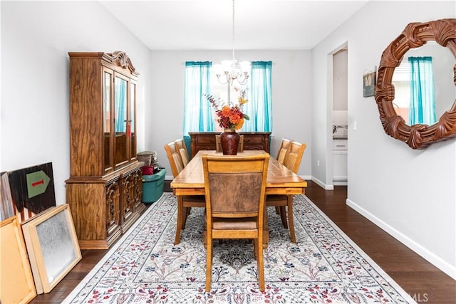 dining space with an inviting chandelier, baseboards, and dark wood-style flooring