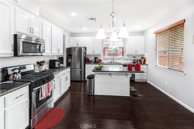 kitchen featuring stainless steel appliances, white cabinetry, a sink, and a kitchen breakfast bar