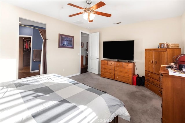 bedroom featuring visible vents, a spacious closet, a ceiling fan, light carpet, and baseboards