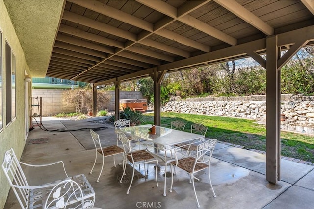 view of patio / terrace featuring a hot tub, outdoor dining area, and a fenced backyard