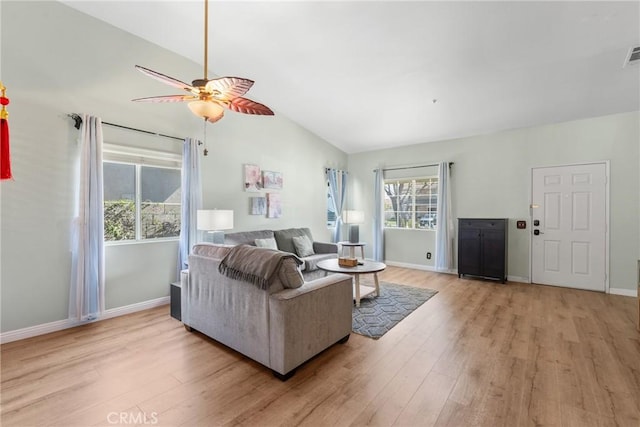 living area with lofted ceiling, baseboards, visible vents, and light wood finished floors