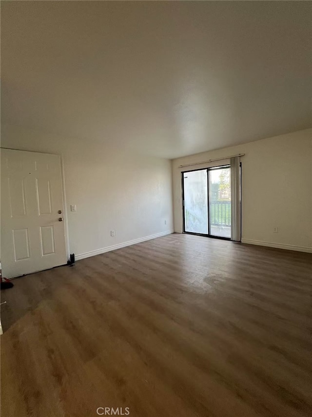 spare room featuring baseboards and wood finished floors