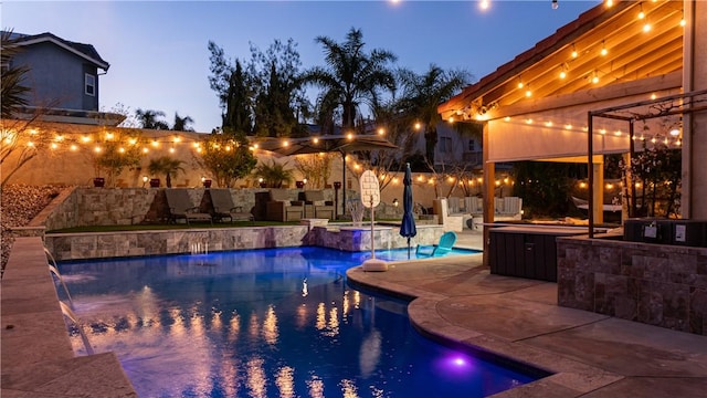 pool at dusk featuring a fenced backyard, a pool with connected hot tub, and a patio