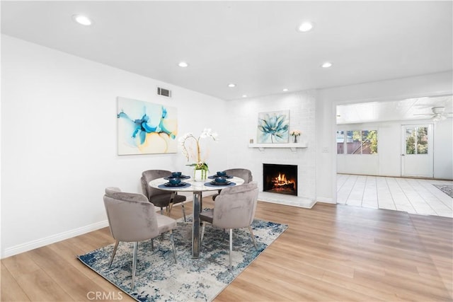 dining room with a fireplace, recessed lighting, visible vents, wood finished floors, and baseboards