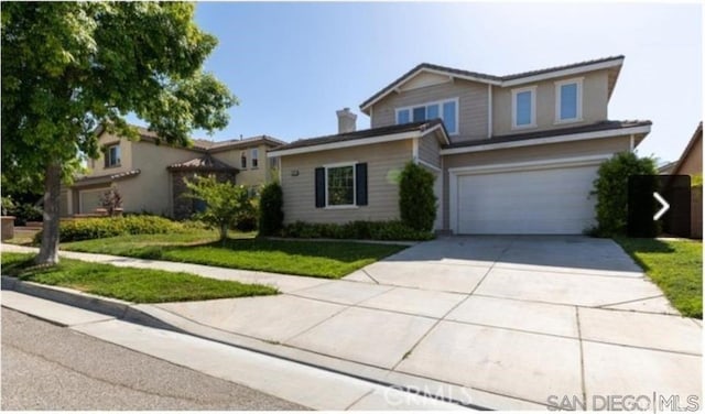 traditional-style home featuring a garage, driveway, and a front lawn