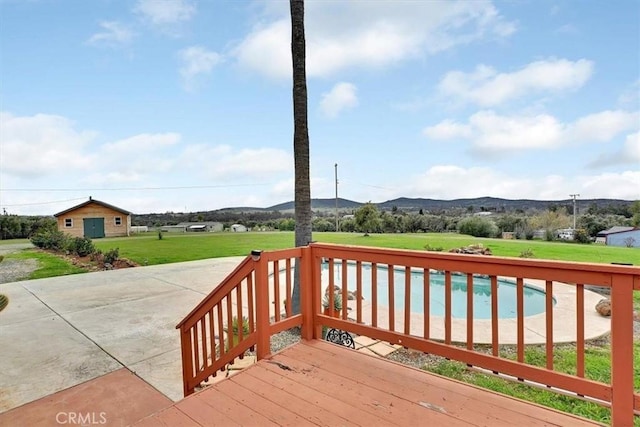 deck featuring a yard, a mountain view, and an outdoor pool