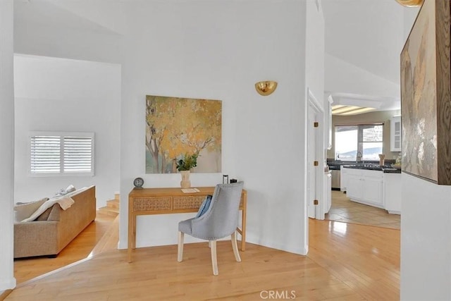 home office featuring high vaulted ceiling and light wood-style floors