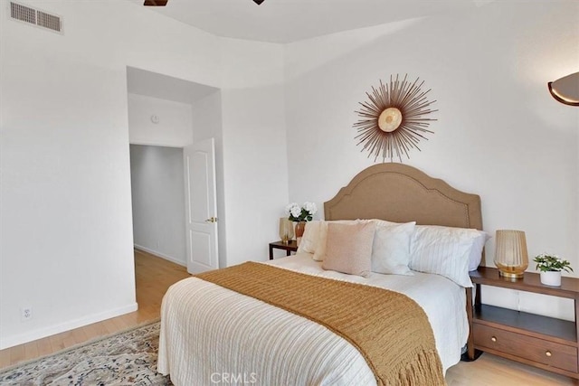 bedroom with baseboards, visible vents, and wood finished floors