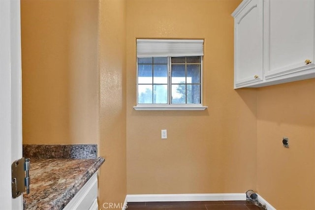 washroom with baseboards, electric dryer hookup, and cabinet space
