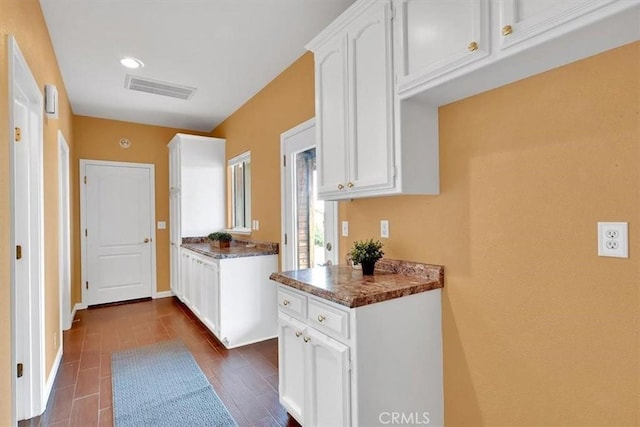 kitchen featuring white cabinets, dark countertops, recessed lighting, baseboards, and visible vents