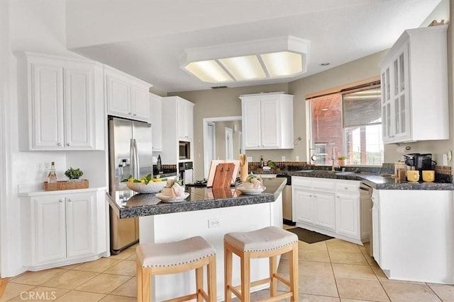 kitchen with white cabinetry, appliances with stainless steel finishes, light tile patterned floors, and a center island