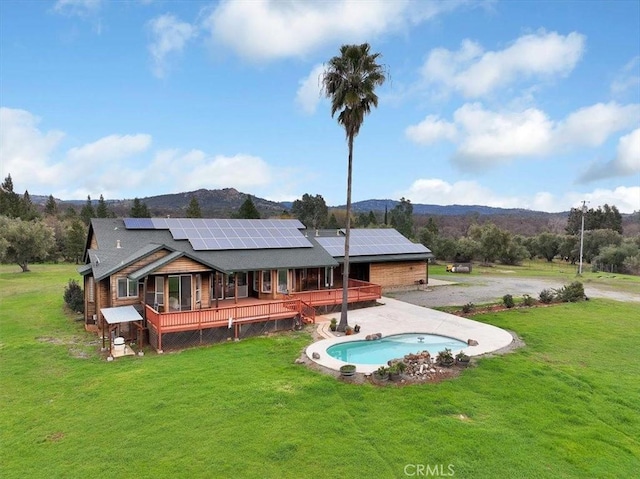 back of house featuring a lawn, a deck with mountain view, and solar panels