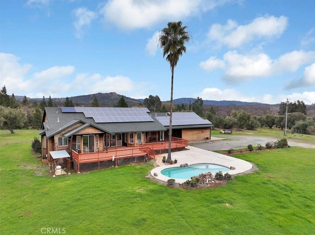 back of house featuring roof mounted solar panels and a yard