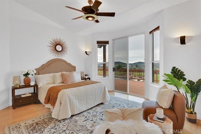 bedroom with wood finished floors, access to outside, a mountain view, a ceiling fan, and vaulted ceiling