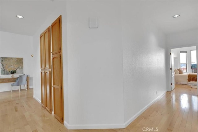 hallway with baseboards, recessed lighting, and light wood-style flooring