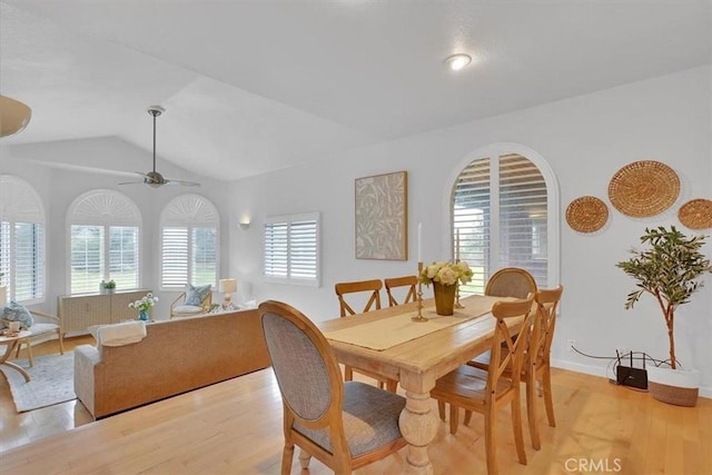 dining room featuring a ceiling fan, baseboards, vaulted ceiling, and light wood-type flooring