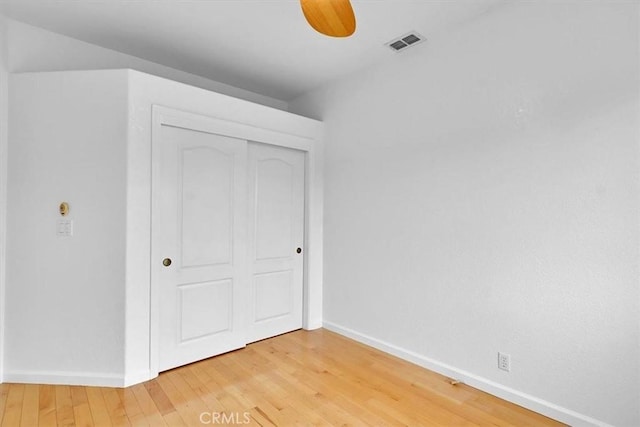 unfurnished bedroom featuring baseboards, visible vents, light wood finished floors, and a closet