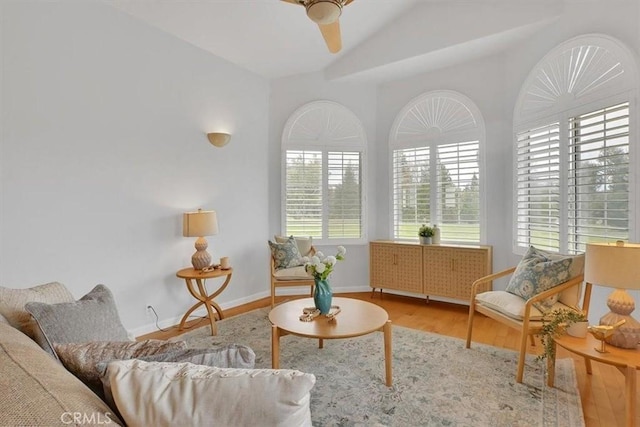 interior space with baseboards, a ceiling fan, wood finished floors, and vaulted ceiling